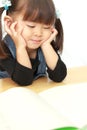 Japanese girl reading a picture book with her chin in her hands Royalty Free Stock Photo